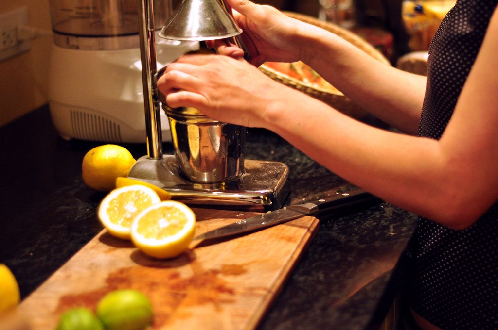 A person turning a hand-operated juicer