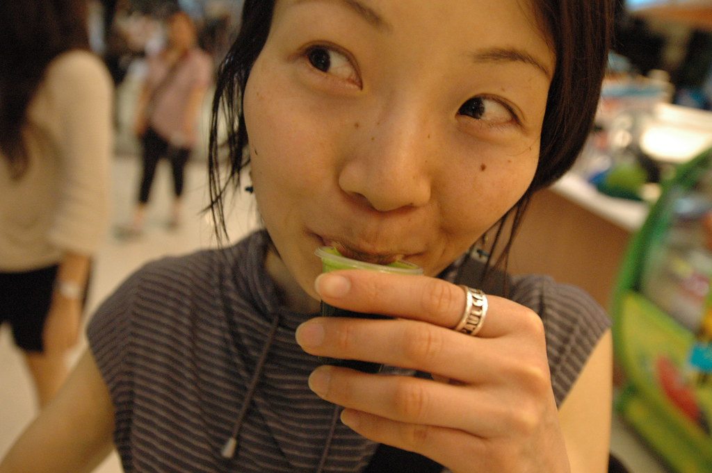 A person drinking green wheatgrass juice