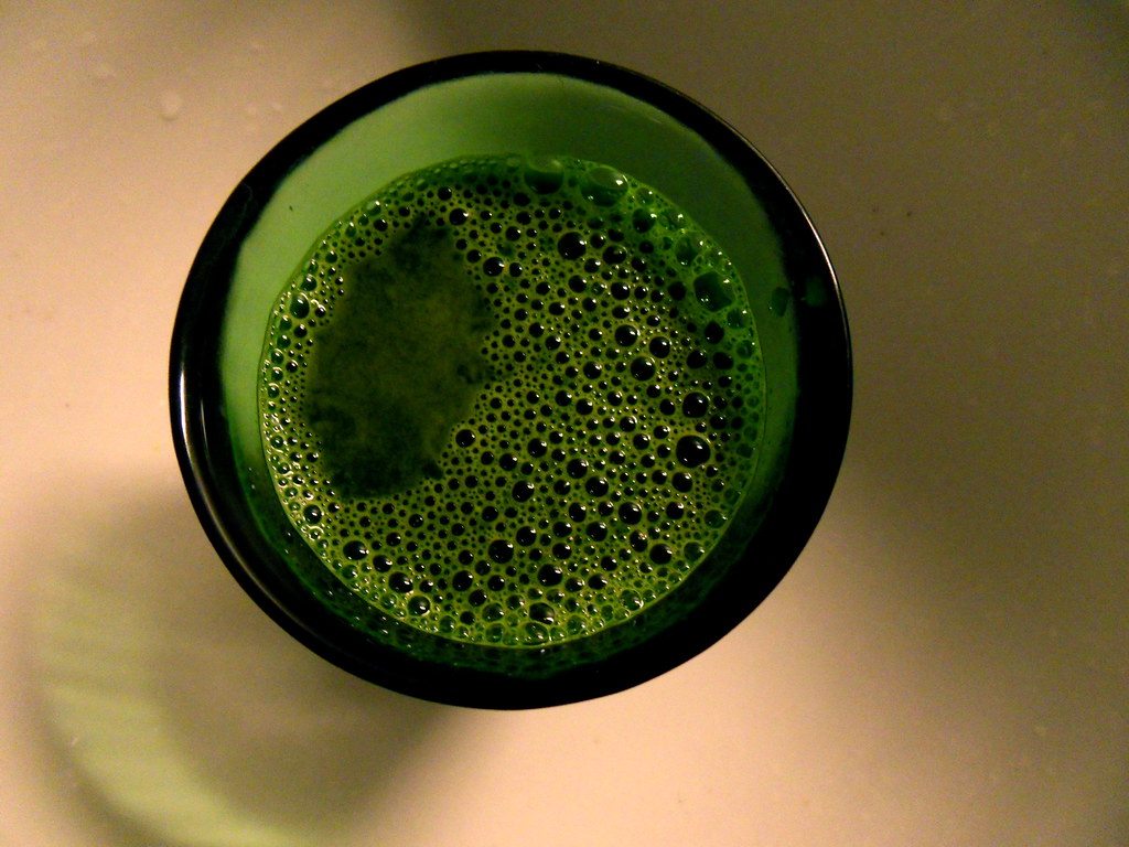 A close-up view of a glass of green juice from above